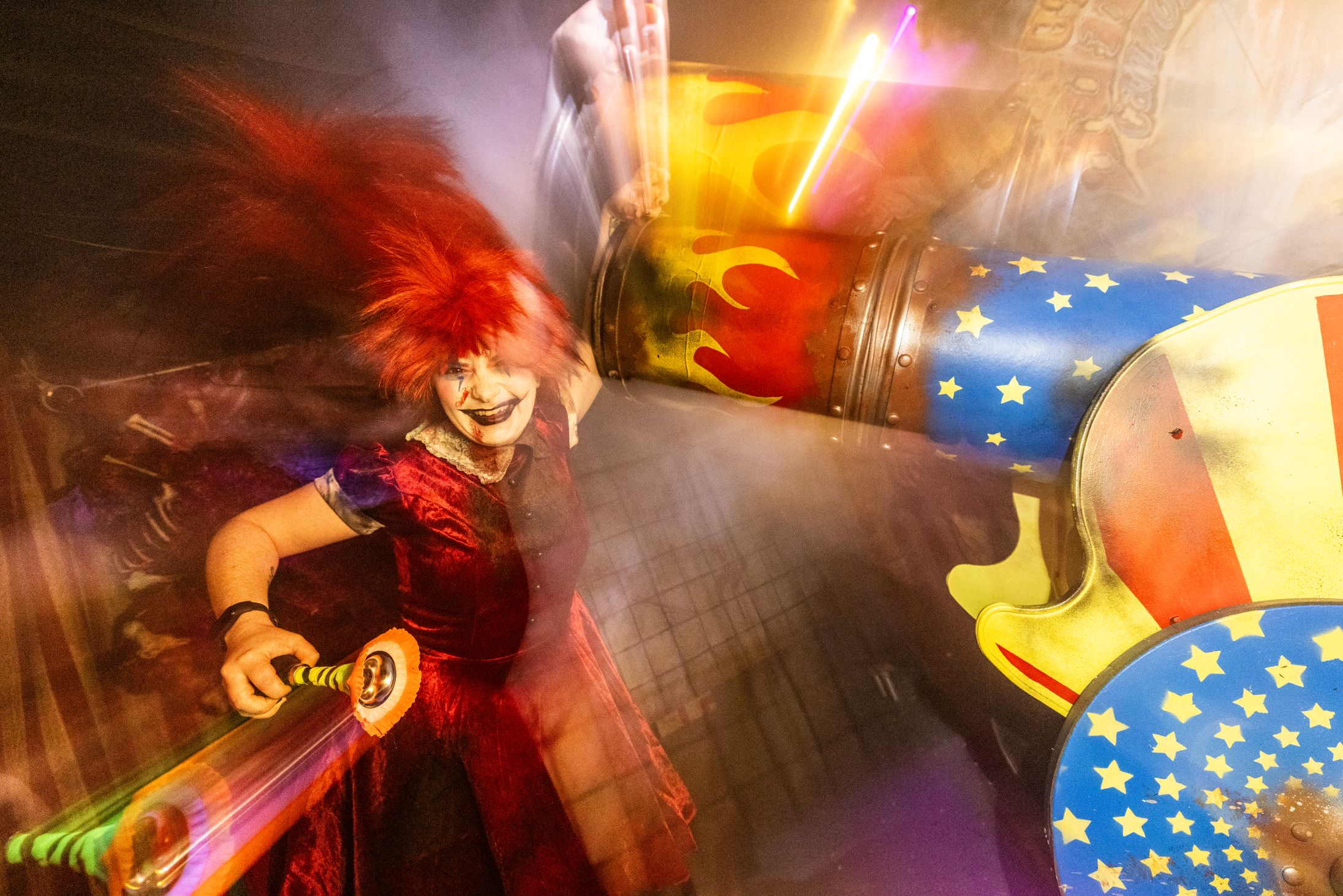 An image of a spooky carnival clown grinning next to an old fashioned circus canon in the Behind The Screams Maze at Luna Park.